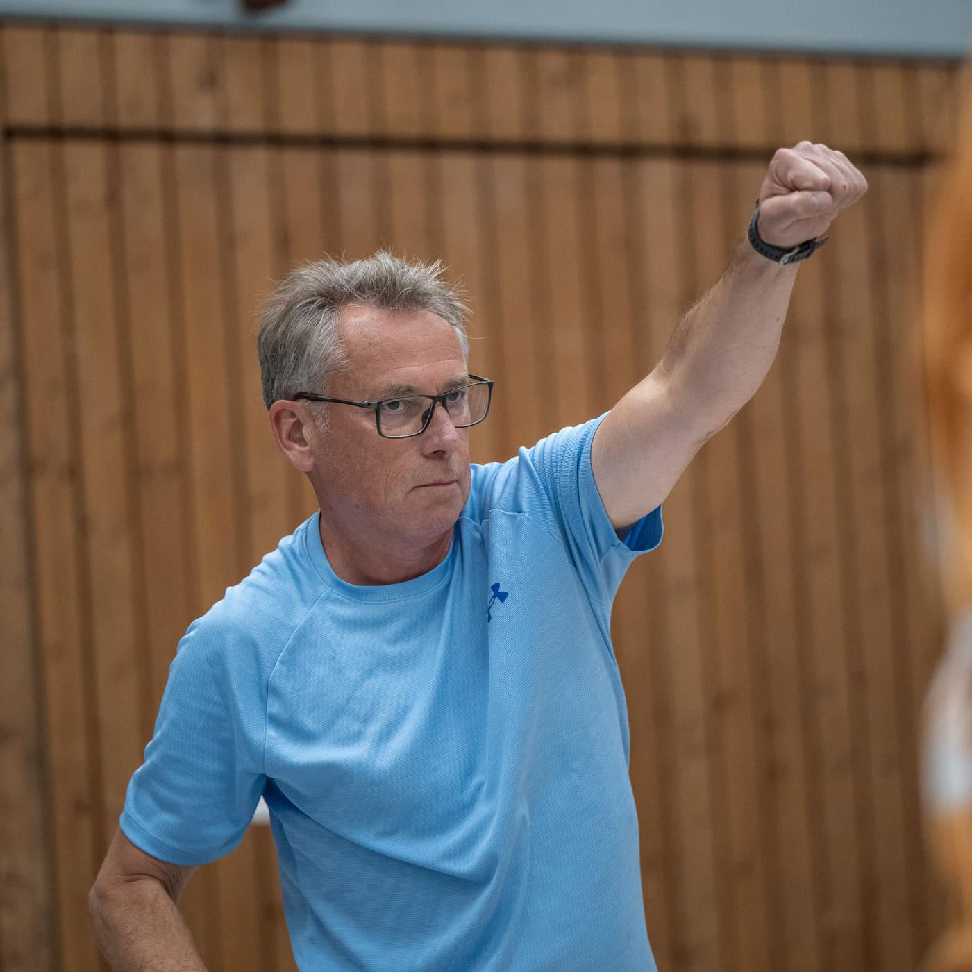 Nahaufnahme eines Sportlers, der beim Aufwärmen den Arm zur Hallendecke streckt