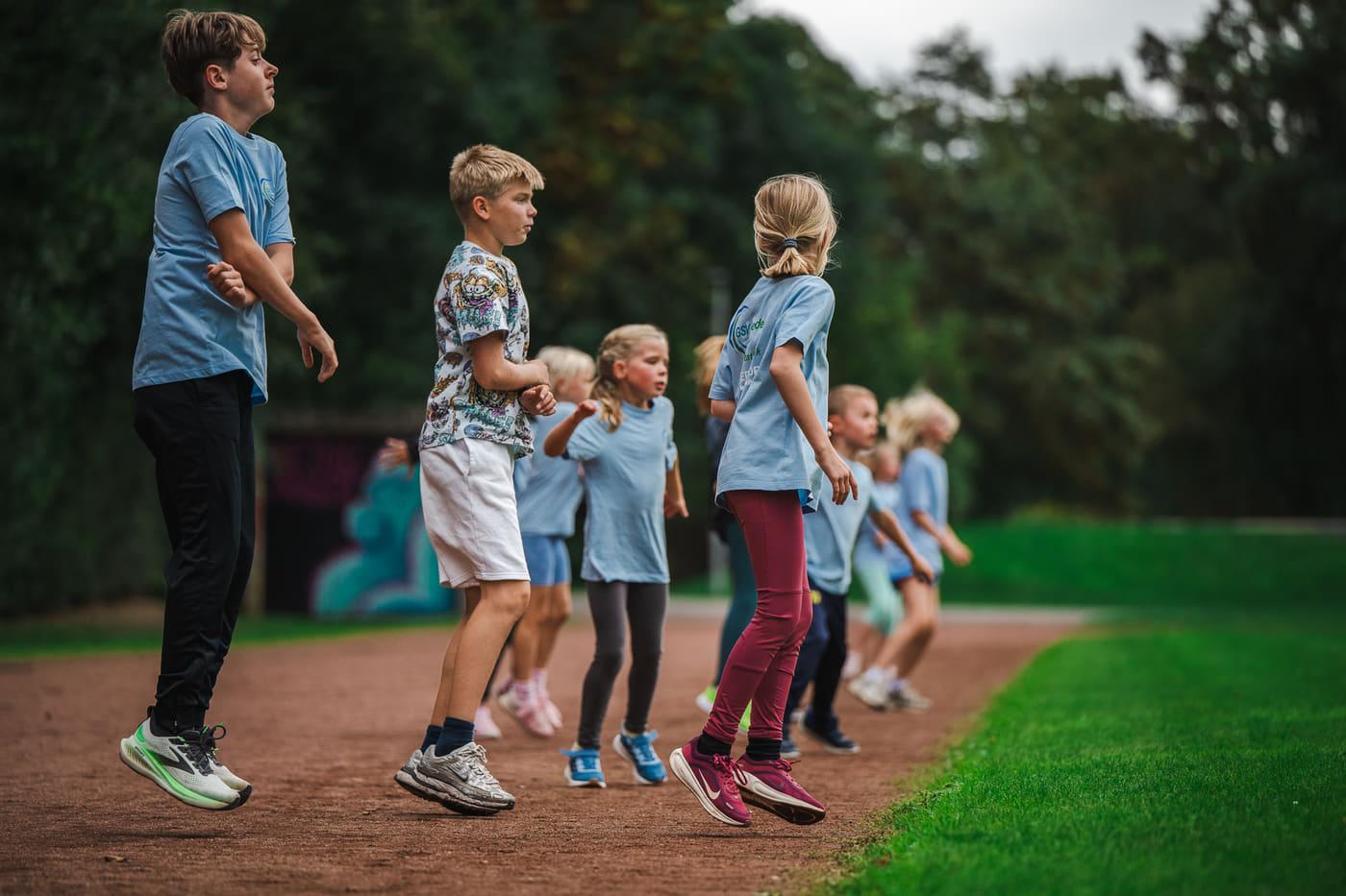 Kinder und Jugendliche üben im Aufwärmprogramm den Hopserlauf
