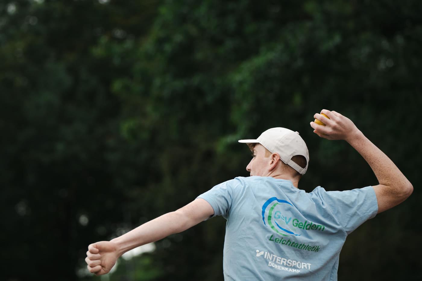 Wurfbewegung im Vereinsshirt der Leichtathletik-Abteilung, der Ball schon in der Luft