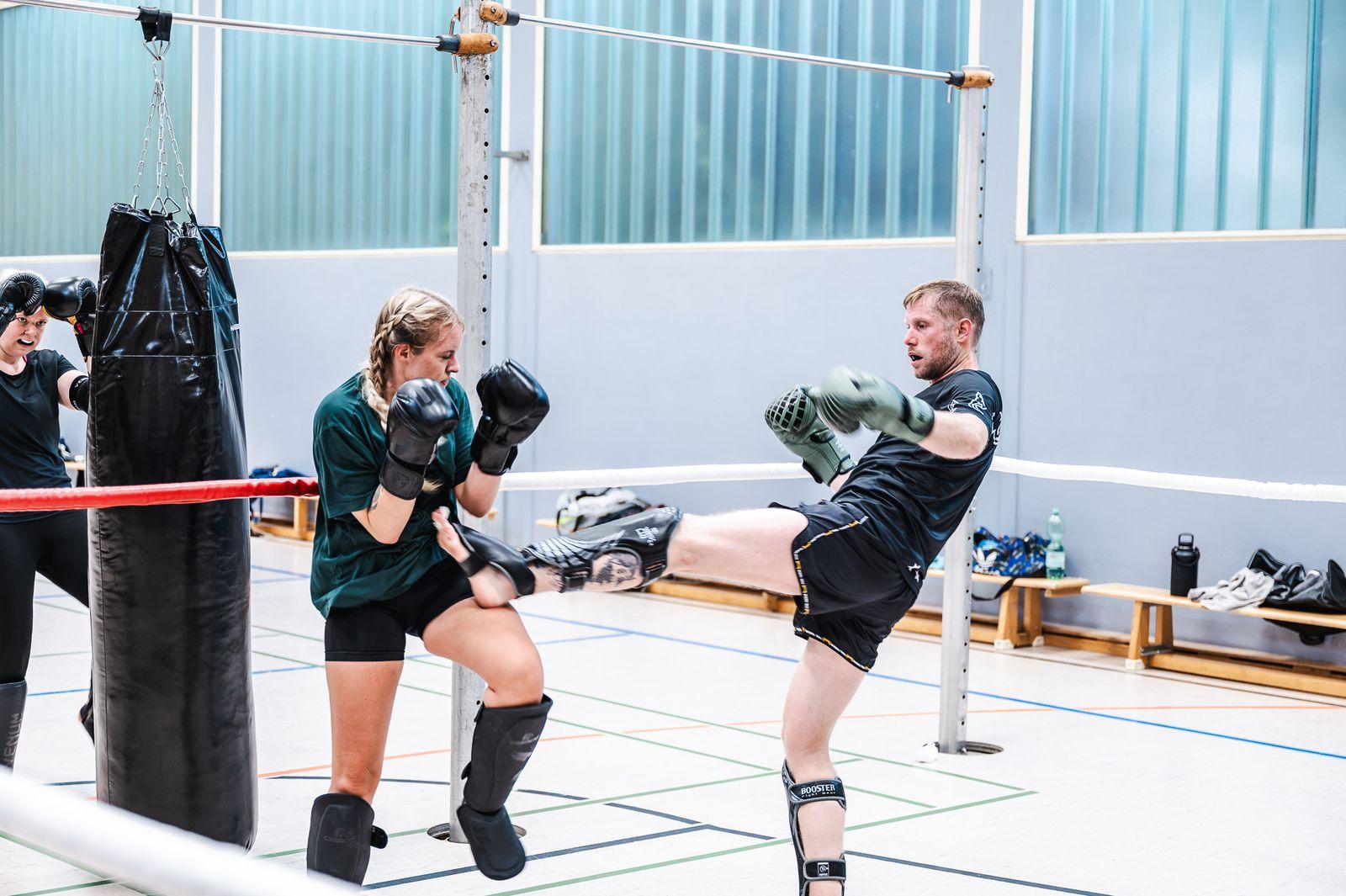Sportlerin führt einen hohen Kick gegen die Pratzen aus