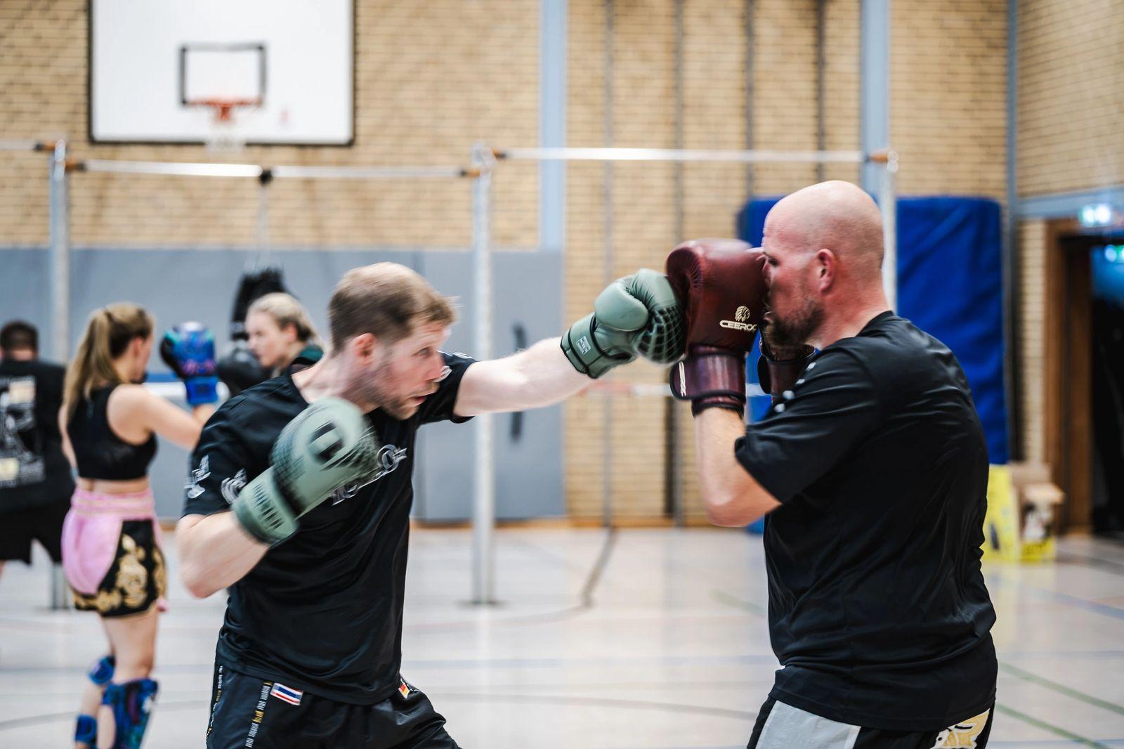 Sportler schlägt gegen die Pratzen seines Trainingspartners
