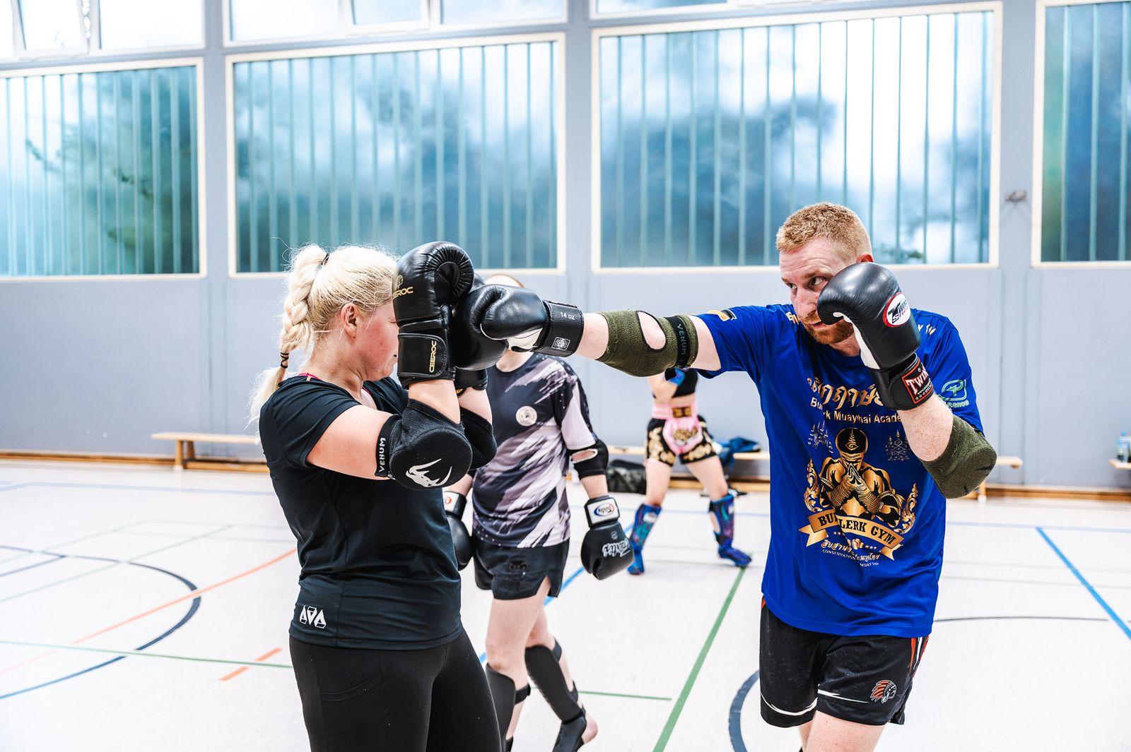 Sportlerin schlägt zu, im Hintergrund trainiert die Gruppe