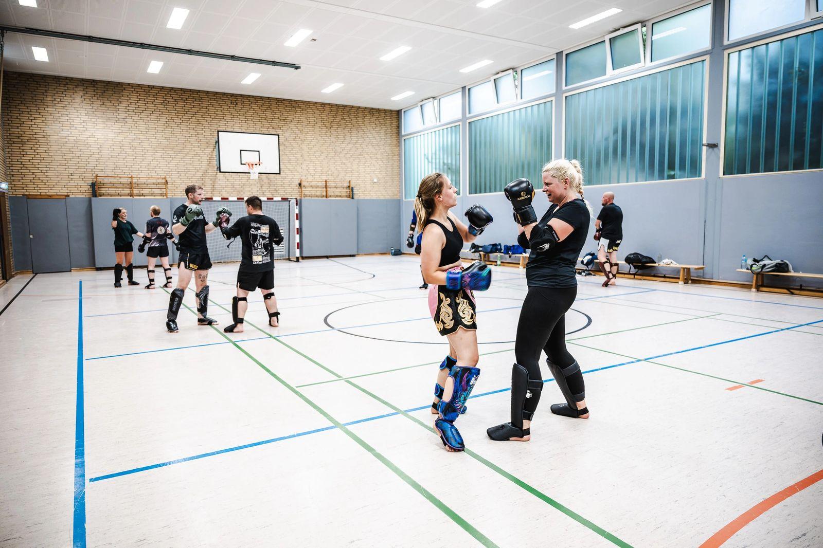 Zwei Trainierende üben im Hintergrund der weiten Sporthalle