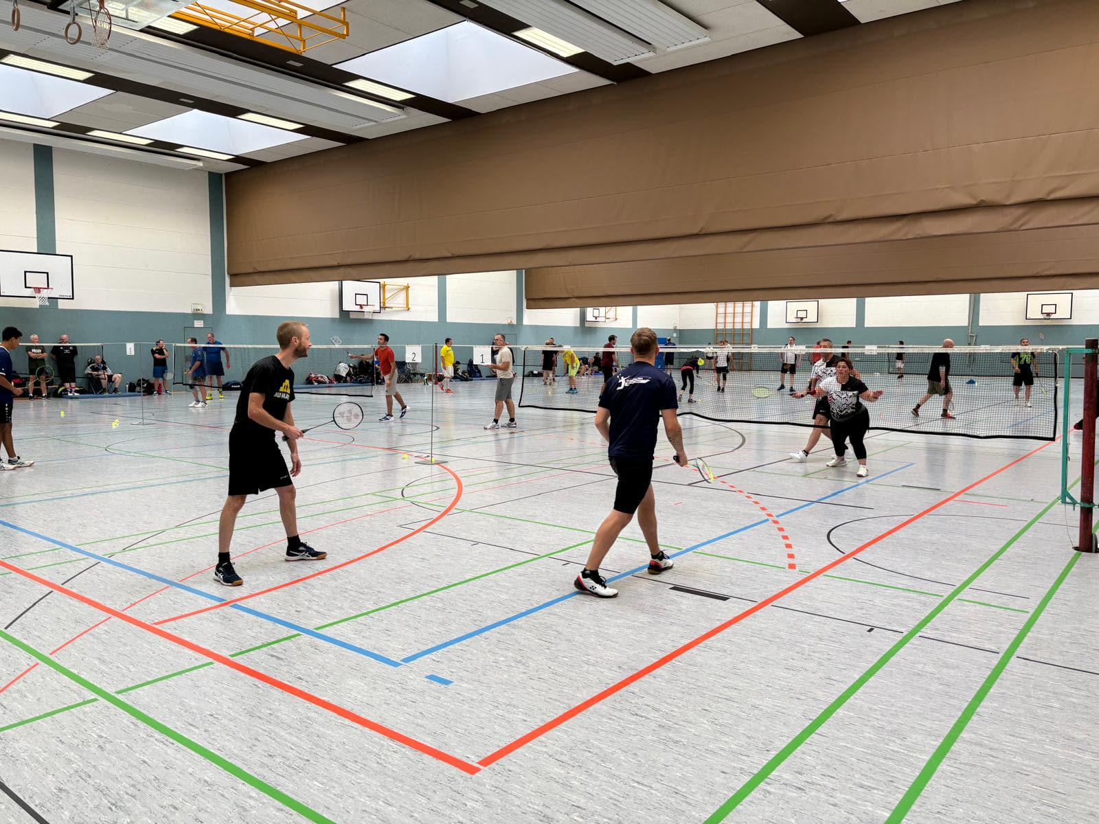 Blick in die Sporthalle mit mehreren bespielten Badmintonfeldern