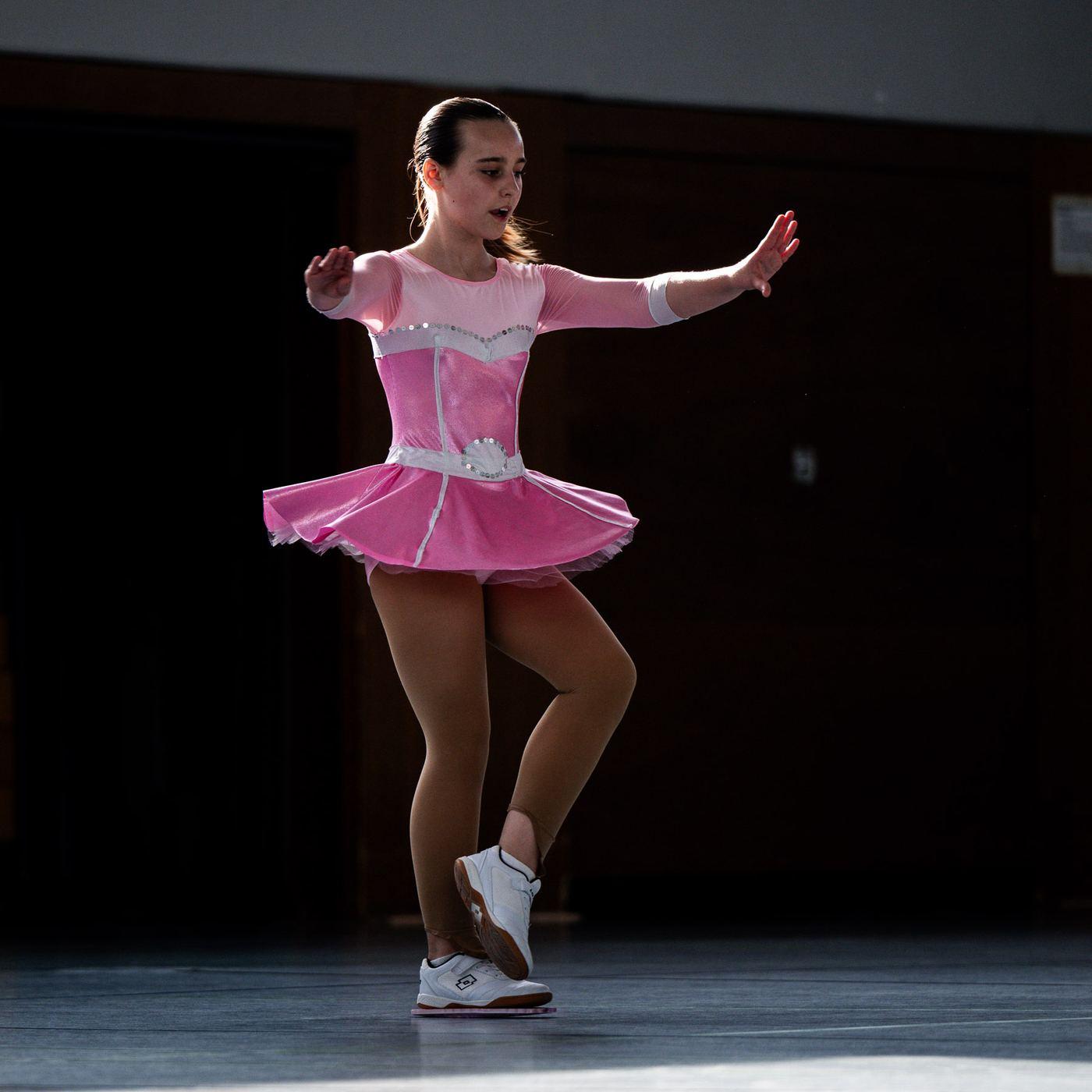 Läuferin im rosa Kleid in einer Pose vor dunklem Hintergrund