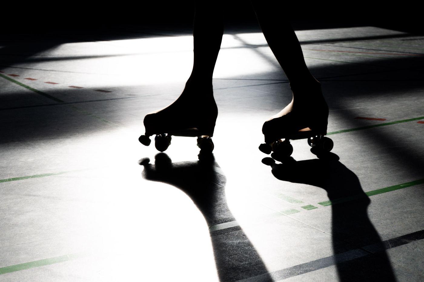 Nahaufnahme von Rollschuhen und ihrem Schatten auf dem Hallenboden
