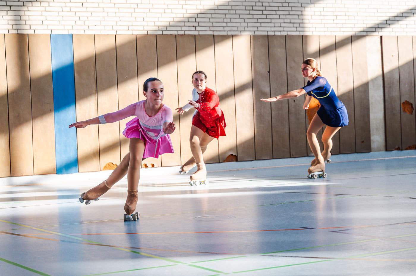 Rollkunstläuferinnen in Wettkampfkleidung auf dem Hallenboden