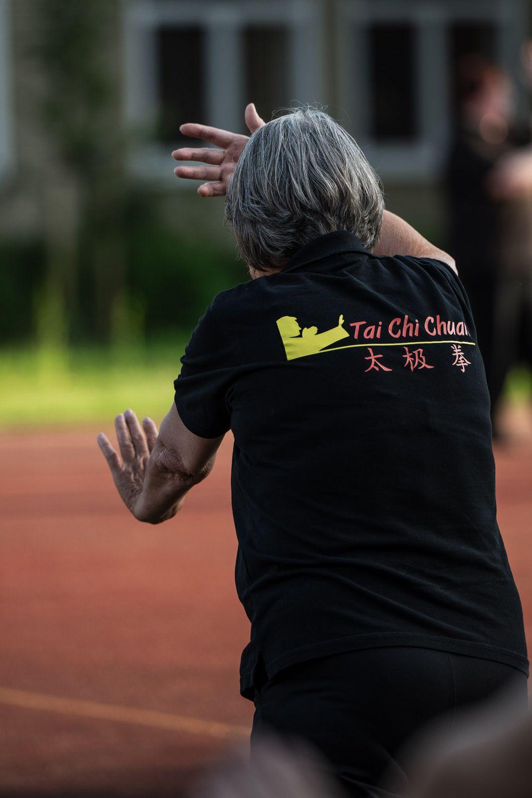 Übende von hinten im Vereinsshirt der Tai-Chi-Gruppe