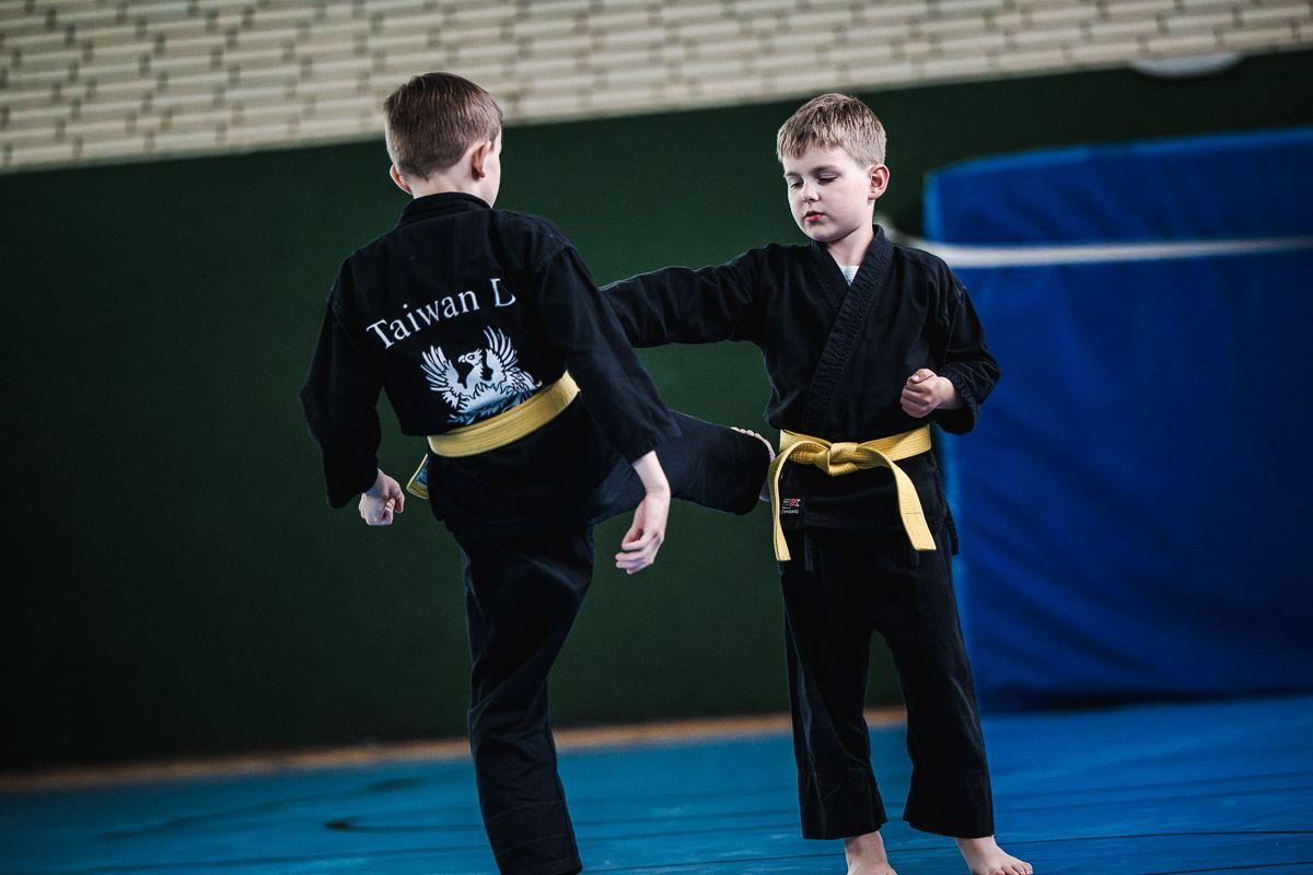 Zwei Jungen üben eine Tritttechnik gegeneinander